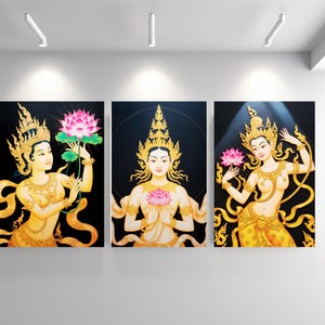 May include: Three framed paintings depicting traditional Asian figures. Each figure is adorned with gold jewelry and headdresses, holding a pink lotus flower against a black background. The figures are in various poses, with flowing garments.