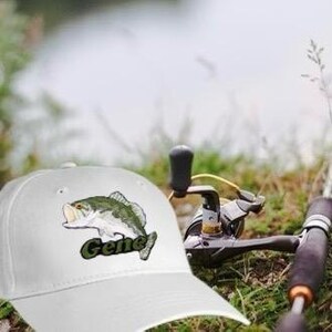 May include: White baseball cap with a green embroidered bass fish and the name "Gene" on the front.