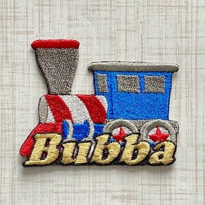 May include: An embroidered iron-on patch shaped like a steam locomotive. The train features a red and white striped boiler, a blue cabin with grey windows, a grey smokestack, and grey wheels with red centers. The name Bubba is stitched in gold.