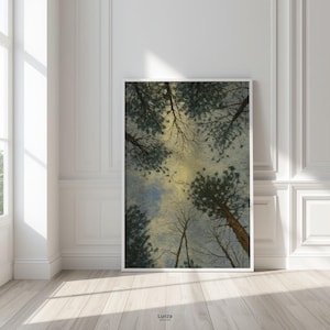 Puede incluir: Una impresión artística enmarcada que presenta una vista hacia arriba a través de árboles altos hacia un cielo nublado. La obra de arte tiene verdes, azules y amarillos apagados. La impresión está en un marco blanco contra una pared blanca.