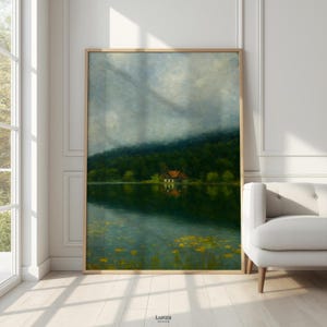 May include: Framed landscape art print featuring a serene lake scene with a small house nestled at the edge of a lush green forest. The artwork has a muted color palette with a cloudy sky and water lilies.