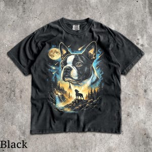 K&ouml;nnte beinhalten: Ein schwarzes Kurzarm-T-Shirt mit einem Grafikdruck eines Boston-Terrier-Kopfes vor einem Nachthimmel mit Vollmond und Sternschnuppen. Unter dem Hund befindet sich die Silhouette eines kleinen Hundes auf einer felsigen Klippe bei einem Wasserfall.