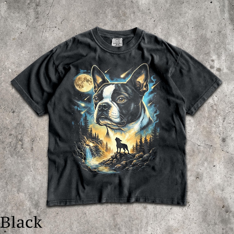 K&ouml;nnte beinhalten: Ein schwarzes Kurzarm-T-Shirt mit einem Grafikdruck eines Boston-Terrier-Kopfes vor einem Nachthimmel mit Vollmond und Sternschnuppen. Unter dem Hund befindet sich die Silhouette eines kleinen Hundes auf einer felsigen Klippe bei einem Wasserfall.