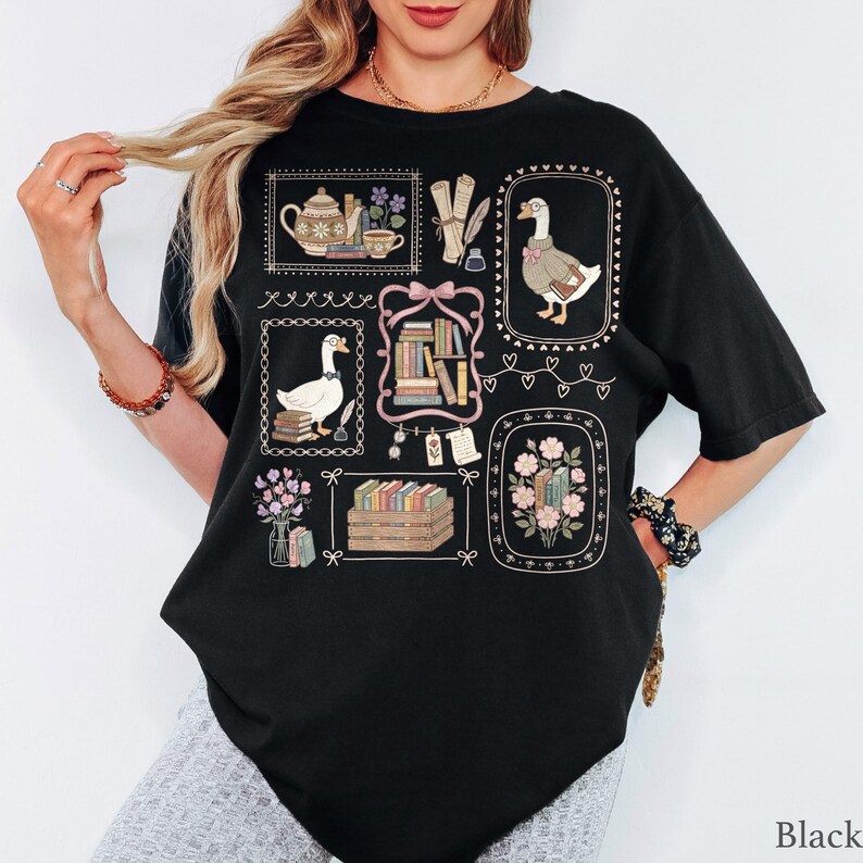 Puede incluir: Una camiseta negra de manga corta con un estampado gr&aacute;fico de varias ilustraciones enmarcadas que incluyen gansos, pilas de libros, una tetera, flores y plumas de escribir, dispuestas en un estilo de collage con bordes decorativos.