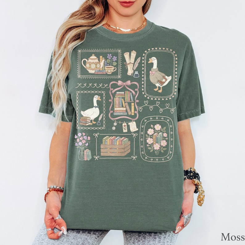 Puede incluir: Una camiseta de manga corta color verde musgo con un estampado gr&aacute;fico de varias ilustraciones enmarcadas que incluyen gansos, pilas de libros, una tetera, una taza, pergaminos y arreglos florales dispuestos en un patr&oacute;n de cuadr&iacute;cula.