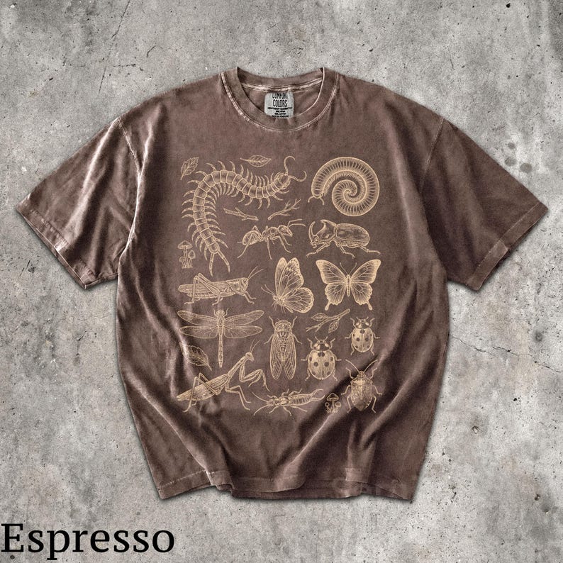 May include: An espresso brown short-sleeve t-shirt featuring a detailed cream-colored graphic print of various insects, including a centipede, butterfly, dragonfly, beetle, and mantis, arranged across the front with the Comfort Colors brand label.