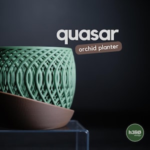 May include: A green, intricately designed orchid planter with a matching brown saucer. The planter has a woven pattern and the word "quasar" is displayed above the text "orchid planter". The design is set against a dark background.
