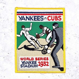 May include: Embroidered patch featuring a baseball game scene with the text "Yankees vs Cubs" and "World Series Yankee Stadium 1932." The patch has a green background with baseball players in action, and a yellow border.