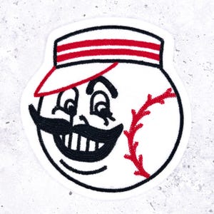 May include: Embroidered patch of a baseball-shaped character with a mustache and a cap with red stripes. The character has a smiling face with black embroidered details and a red baseball stitch.