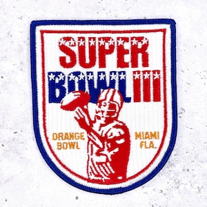 May include: A rectangular patch with a blue border, red and white interior, and the words "SUPER BOWL III." It features a football player in red and white, holding a football. The text "ORANGE BOWL MIAMI FLA." is also visible.