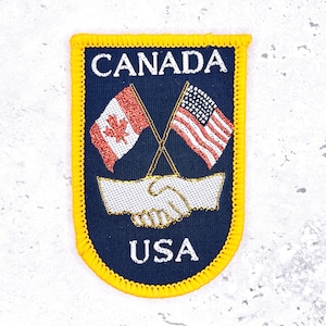 May include: A white ceramic mug with a black handle and the text "But First, Coffee" in a black, bold font. The mug is sitting on a wooden surface. The mug is approximately 4 inches tall.