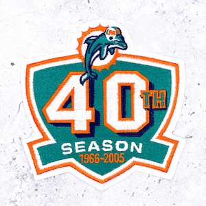 May include: Embroidered patch featuring the Miami Dolphins logo, a leaping dolphin, and the number "40" in white on a teal and orange shield. The text "SEASON 1966-2005" is also included. The patch is a commemorative item.