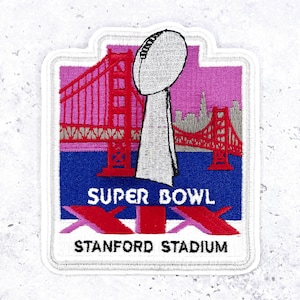 May include: An embroidered patch featuring a white football trophy centered over a red Golden Gate Bridge silhouette against a pink sky and blue water. Text reads SUPER BOWL XIX and STANFORD STADIUM in black and white lettering.