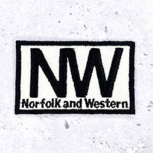 May include: A rectangular embroidered patch featuring a white background with a thick black border. The letters NW are prominently displayed in large black font, with the text Norfolk and Western printed in smaller black letters below.