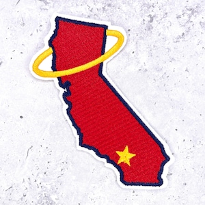 May include: An embroidered patch in the shape of the state of California. The patch features a red center with a dark blue border, a yellow star in the lower portion, and a yellow halo-like ring encircling the upper section of the state shape.