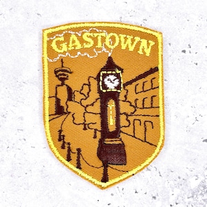 May include: Embroidered patch in a shield shape featuring the text "GASTOWN" above a detailed illustration of a clock tower and buildings. The patch is primarily gold and brown with white and black accents.