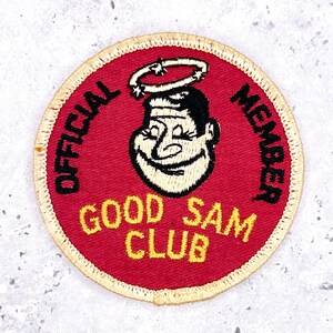May include: A circular red patch with the words "OFFICIAL MEMBER GOOD SAM CLUB" in black and yellow. It features a smiling cartoon face with a halo. The patch has a cream-coloured border.