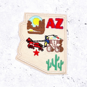 May include: Embroidered patch in the shape of Arizona, featuring a desert landscape, the letters "AZ", a horse-drawn wagon, a red star, and cacti. The patch has a tan background with colorful stitching.