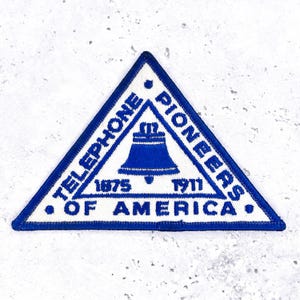 Könnte beinhalten: Eine weiße Keramik-Tasse mit schwarzem Henkel und dem Text "But First, Coffee" in fetter, schwarzer Schrift. Die Tasse steht vor einem verschwommenen Hintergrund, der eine gemütliche Umgebung suggeriert.