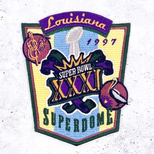 May include: Embroidered patch featuring the text "Louisiana" and "Super Bowl XXXI 1997 Superdome." The patch has a shield shape with a yellow, blue, and green background. Includes a football, musical instrument, and a bird.