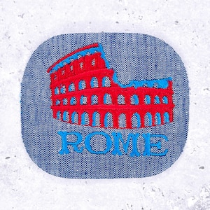 May include: Embroidered patch featuring the Colosseum in Rome, Italy. The iconic landmark is rendered in red and blue thread against a denim-like background. The word "ROME" is embroidered in blue below the structure.