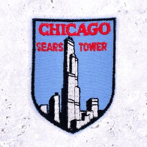 May include: Embroidered patch depicting the Chicago Sears Tower, now known as the Willis Tower. The patch has a light blue background with the words "CHICAGO" and "SEARS TOWER" in red. The tower is shown in black and white.