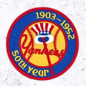 May include: A circular embroidered patch featuring a yellow baseball with red stitching, a red bat, and a red, white, and blue top hat. The blue border displays the yellow text 1903-1952 50TH YEAR, while the center features the red script Yankees.