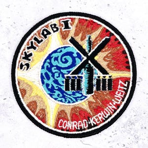 May include: A white ceramic mug with a black handle and the text "But First, Coffee" in a handwritten style. The mug is on a white surface. The mug is approximately 4 inches tall.