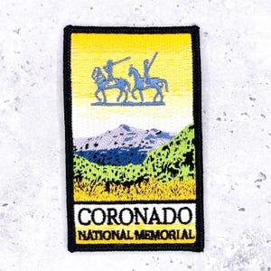 May include: Embroidered patch featuring a yellow sky, blue riders on horses, and a mountain landscape. The patch includes the text "CORONADO NATIONAL MEMORIAL" in white letters on a black background, with a black border.