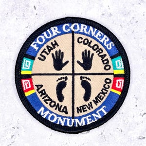May include: A circular embroidered patch featuring the Four Corners Monument. The design is divided into four quadrants on a beige background, labeled Utah, Colorado, Arizona, and New Mexico, with black handprints and footprints in each section.