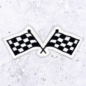 May include: Two crossed black and white checkered flags patch with a white border. The flags are embroidered with a classic racing design, perfect for adding to jackets, bags, or other apparel. The patch is set against a light gray textured background.