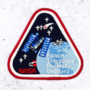 Stara naszywka projektu teleskopu kosmicznego NASA • Centrum Kosmiczne Goddarda z lat 80. XX wieku • Pamiątkowa odznaka misji