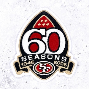 Puede incluir: Parche bordado con un diseño negro, rojo y dorado. El parche presenta el número "60" en blanco, el texto "SEASONS 1946-2006" y el logotipo del equipo. El parche tiene forma de escudo.