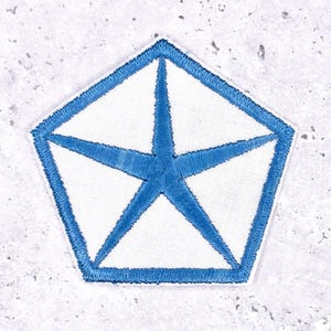 May include: A white, pentagon-shaped patch with a blue embroidered outline and a blue star design in the center. The patch has a textured, fabric appearance and is likely an emblem or insignia.