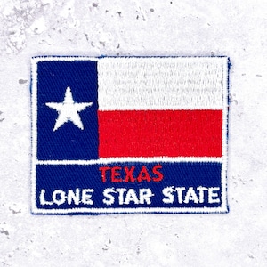 May include: Embroidered patch featuring the Texas state flag. The design includes a blue vertical stripe with a white star, a white horizontal stripe, and a red horizontal stripe. The words "TEXAS" and "LONE STAR STATE" are also embroidered.