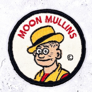 May include: Embroidered patch featuring the cartoon character Moon Mullins. The patch has a white background with a black border. The character is wearing a yellow hat and jacket, with the words "MOON MULLINS" in red.