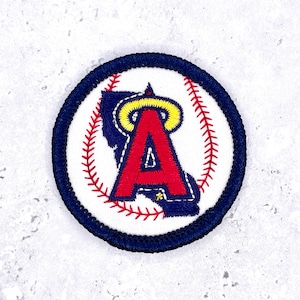 May include: A circular embroidered patch featuring a white background with red baseball stitching patterns. In the center, a large red letter A is outlined in dark blue with a yellow halo above it, all enclosed by a thick dark blue stitched border.