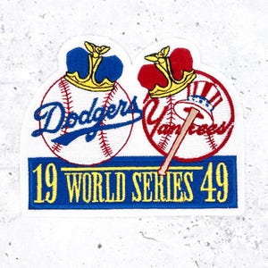 May include: Embroidered patch featuring baseballs with crowns, representing the Dodgers and Yankees. The patch includes the text "19 WORLD SERIES 49" in blue and yellow, on a white background.