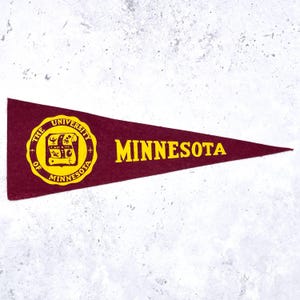 May include: A maroon felt pennant featuring the yellow text MINNESOTA and a circular seal with the words THE UNIVERSITY OF MINNESOTA surrounding a central emblem that depicts a scroll, a lamp, and other symbols in yellow on a maroon background.