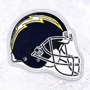 May include: Embroidered patch featuring a navy blue football helmet with a yellow lightning bolt design. The helmet has a white face mask and is outlined with silver thread. This patch is suitable for jackets, bags, or other fabric items.