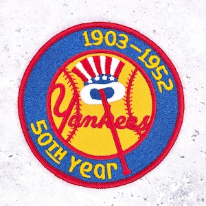 May include: Embroidered patch featuring a baseball design with the text "Yankees" in red script. The patch includes the years "1903-1952" and "50th Year" in yellow lettering, set against a blue and yellow background.
