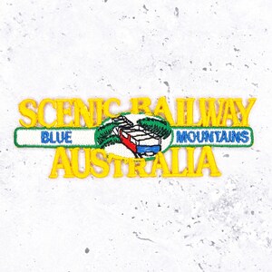 May include: Embroidered patch with the text "SCENIC RAILWAY BLUE MOUNTAINS AUSTRALIA" in yellow, green, and white. The design includes a train and trees, ideal for travel enthusiasts and souvenir collectors.