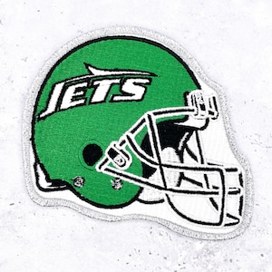 May include: Embroidered patch depicting a green American football helmet with the word "JETS" in white. The helmet has a black facemask and a silver border. Ideal for customising clothing or accessories.