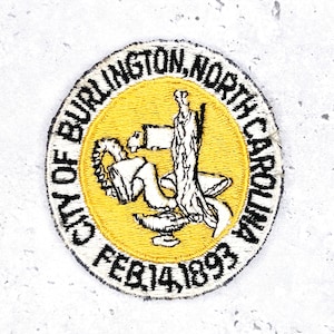 Puede incluir: Parche bordado circular con la inscripción "CITY OF BURLINGTON, NORTH CAROLINA". Un círculo amarillo en el centro tiene una ilustración en blanco y negro. La fecha "FEB. 14, 1893" está en la parte inferior.