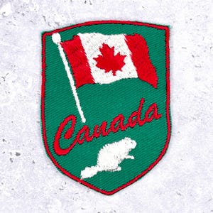 May include: Embroidered patch with the Canadian flag and the word "Canada" in red script. A white beaver is at the bottom. The patch has a green background and a red border.