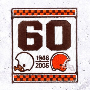 May include: Embroidered patch with the number "60" in brown, two football helmets, and the years "1946" and "2006". The patch has a white background and a brown and orange checkered border.