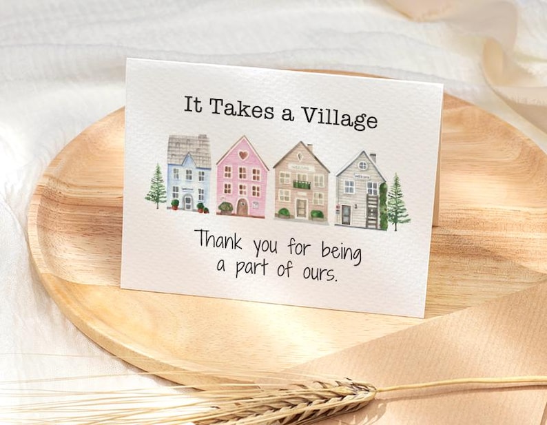 Op de afbeelding: Een wenskaart met de tekst "It Takes a Village" en "Thank you for being a part of ours." De kaart toont aquarel illustraties van vier kleurrijke huizen en twee kleine groenblijvende bomen.