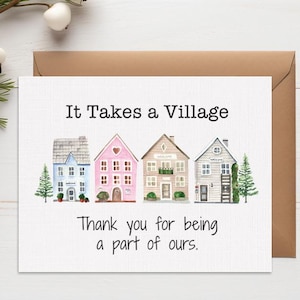 Op de afbeelding: Een wenskaart met de tekst "It Takes a Village" en "Thank you for being a part of ours." De kaart bevat aquarel illustraties van kleurrijke huizen. Achter de kaart zit een bruine envelop, met decoratieve elementen.