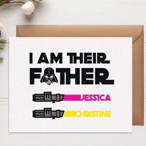 May include: A white greeting card with the text "I AM THEIR FATHER" and a Darth Vader graphic. Below are two lightsaber designs with the names "JESSICA" and "CHRISTINE" in pink and yellow. The card is on a white wooden surface.