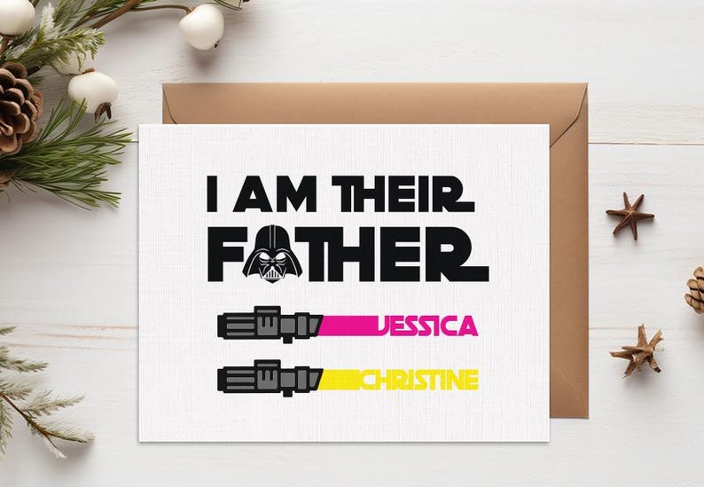 May include: A white greeting card with the text "I AM THEIR FATHER" and a Darth Vader graphic. Below are two lightsaber designs with the names "JESSICA" and "CHRISTINE" in pink and yellow. The card is on a white wooden surface.